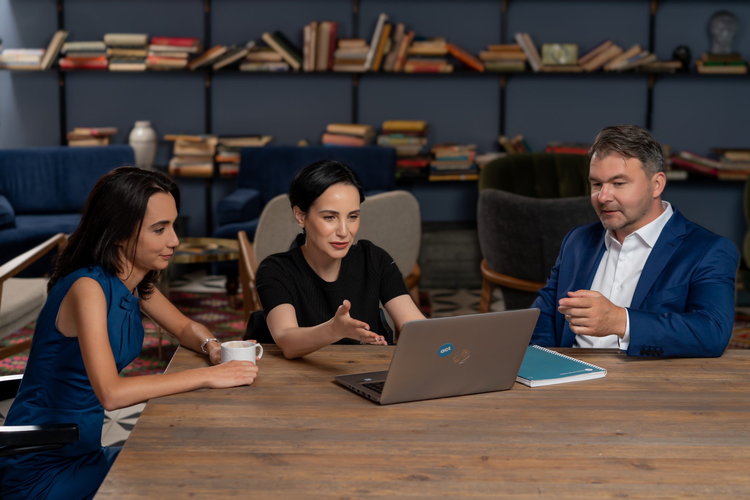 Partners from act legal Romania siting at a table with a laptop in front of them.